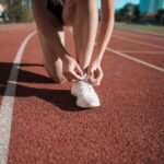 Close-up of a woman tying her shoes on a running track, ready to sprint.