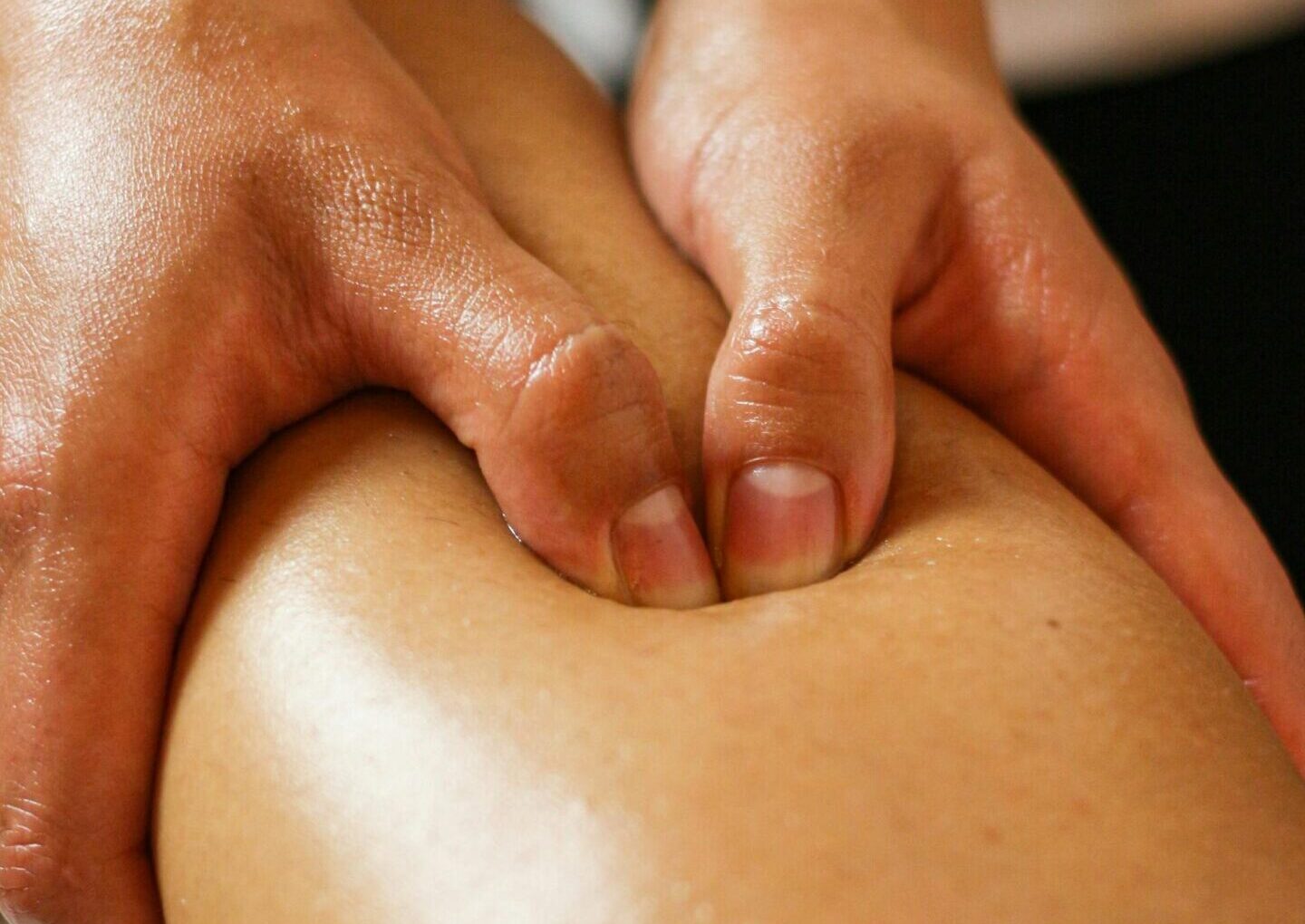 Close-up of hands applying pressure on a leg during a therapeutic massage session.