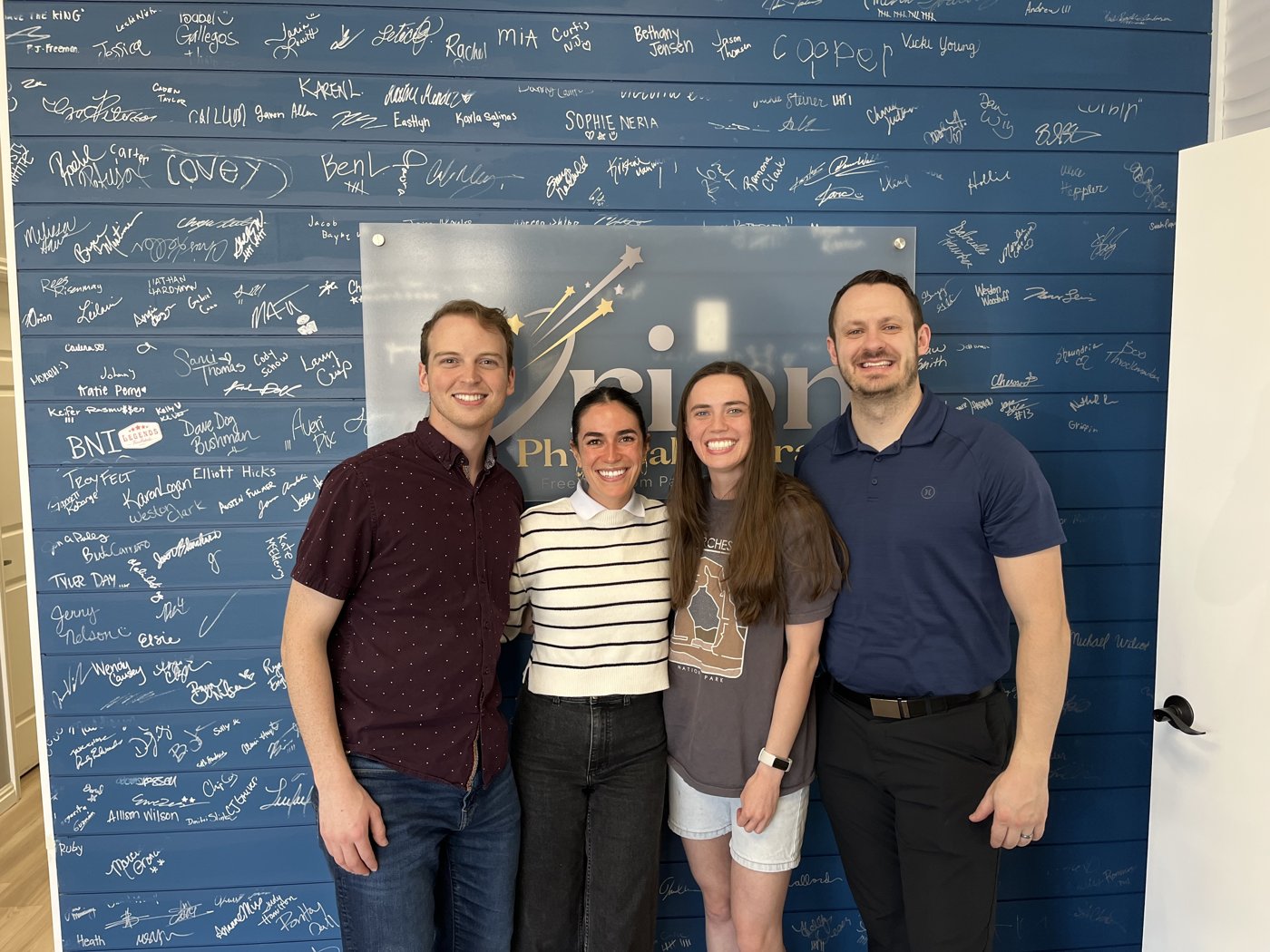 The Orion Physical Therapy team at the patient signature wall in the Springville, UT clinic